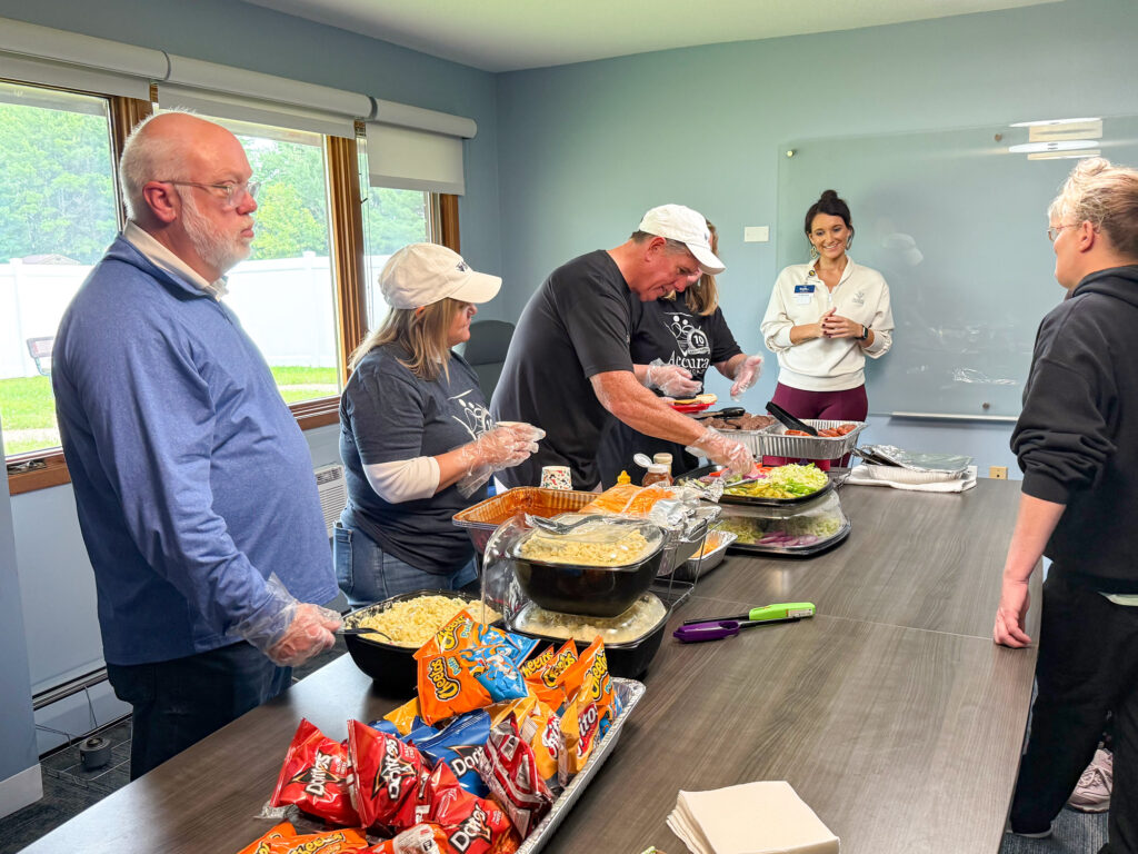 Accura HealthCare Resource Center team members serving a cookout at Traditions Memory Care of Newton