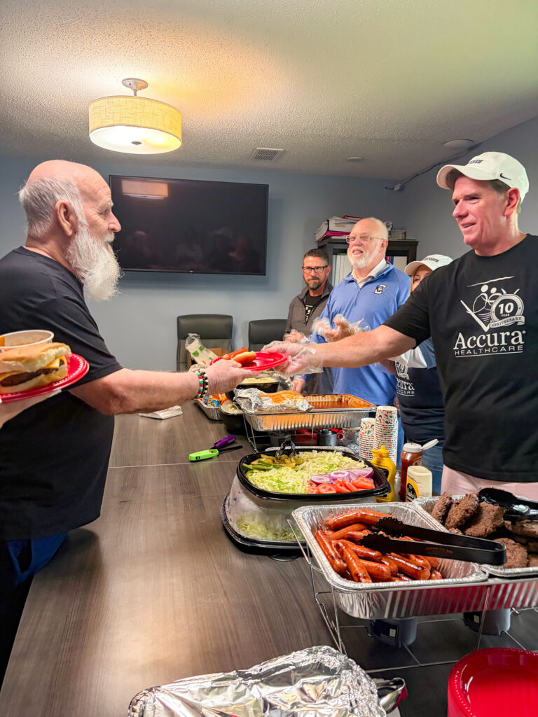Accura HealthCare Resource Center team members serving food during the Traditions Memory Care of Newton Silver Award cookout